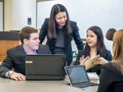 Photo of faculty and students pointing at something on an iPad.