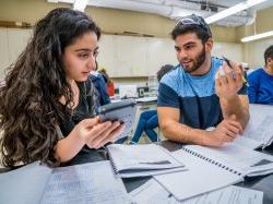 Photo of students at lab bench calculating results.