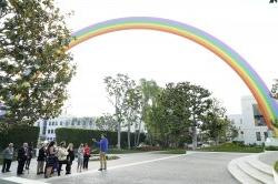 Photo of a group of people standing in front of a giant rainbow sculpture