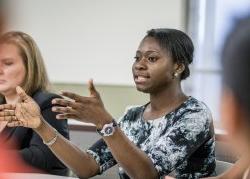 Photo of a young woman explaining a point in her class